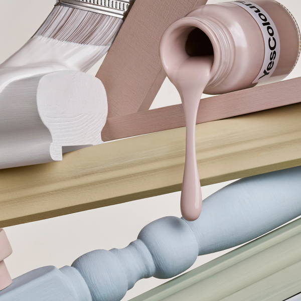 a vertically arranged collection of paint sample jars and painting accessories and tools in soft pastel colours, photographed on a warm white background