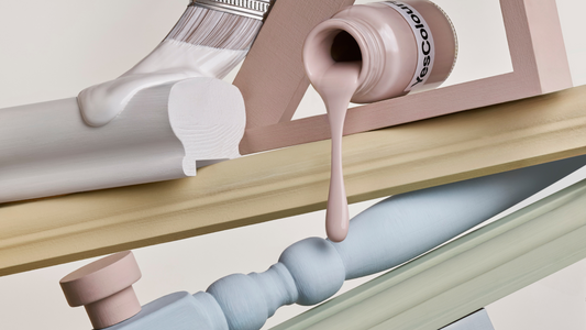 a vertically arranged collection of paint sample jars and painting accessories and tools in soft pastel colours, photographed on a warm white background