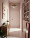 hallway drenched in a soft muted pale peachy pink. midcentury sideboard on the left. red framed mirror on the right, standing on the floor against the bookshelf