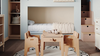 Children's bedroom with bunk beds, wooden furniture, and a round rug with letters.