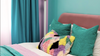 Colorful bedroom with pink walls, teal curtains, and multicolored pillows on a bed.